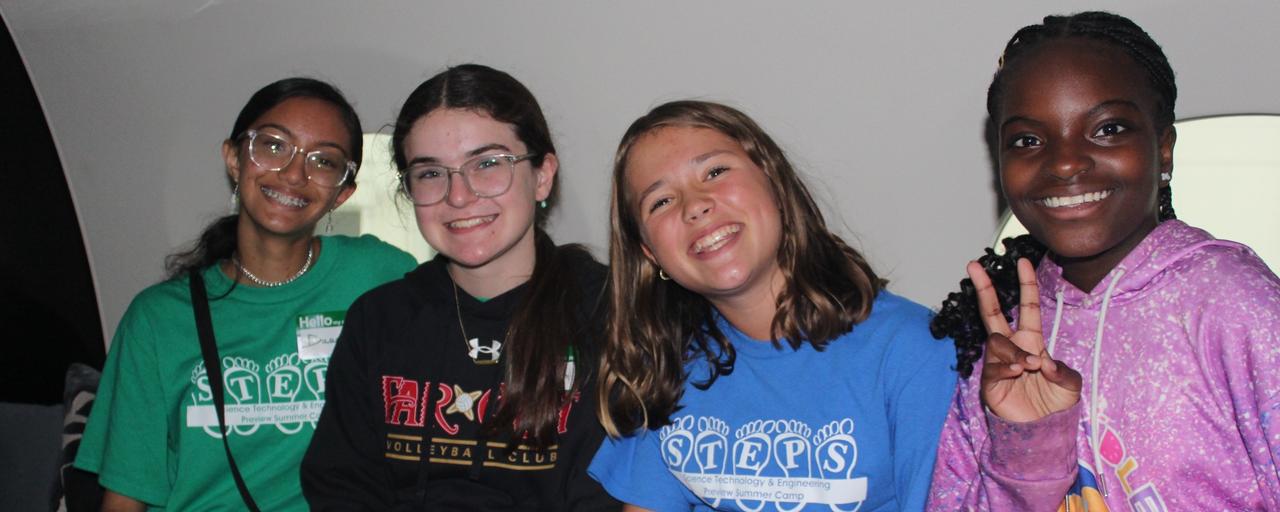 Four campers smile in Amway's private jet as they attend a field trip
